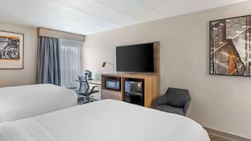 A hotel room with two beds, a desk with a computer, a flat-screen TV, and a chair.