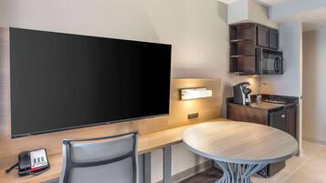 Una cocina moderna con televisor de pantalla plana, microondas integrado y cafetera.