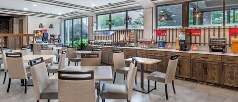 Un restaurante moderno con mostrador, zona de mesas grandes y amplios ventanales.