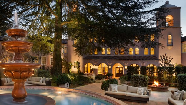 A courtyard with a fountain, outdoor seating, and a building with arched windows and a fire pit. - Fairmont Sonoma Mission Inn & Spa (Sonoma)