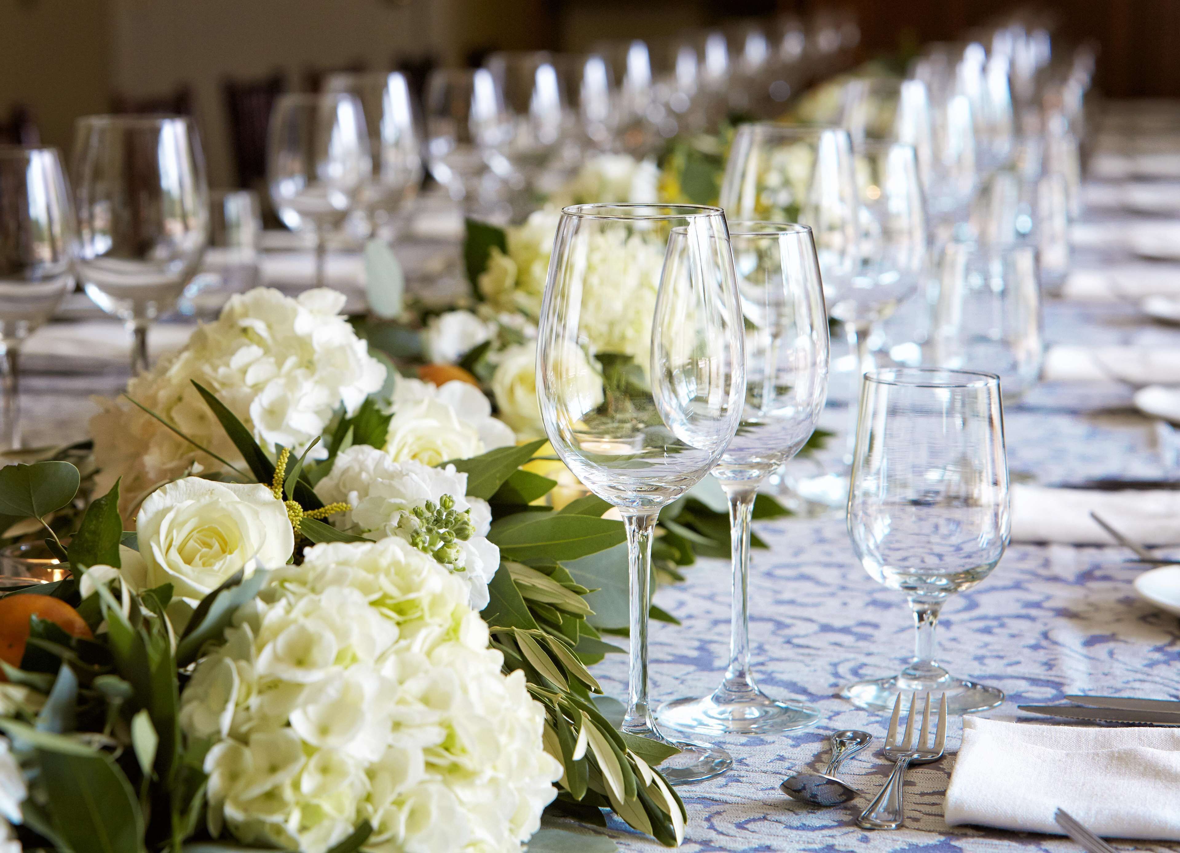 A long table set with multiple wine glasses and a floral centerpiece.