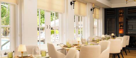 A dining area with multiple tables, chairs, and a view of the outdoors.