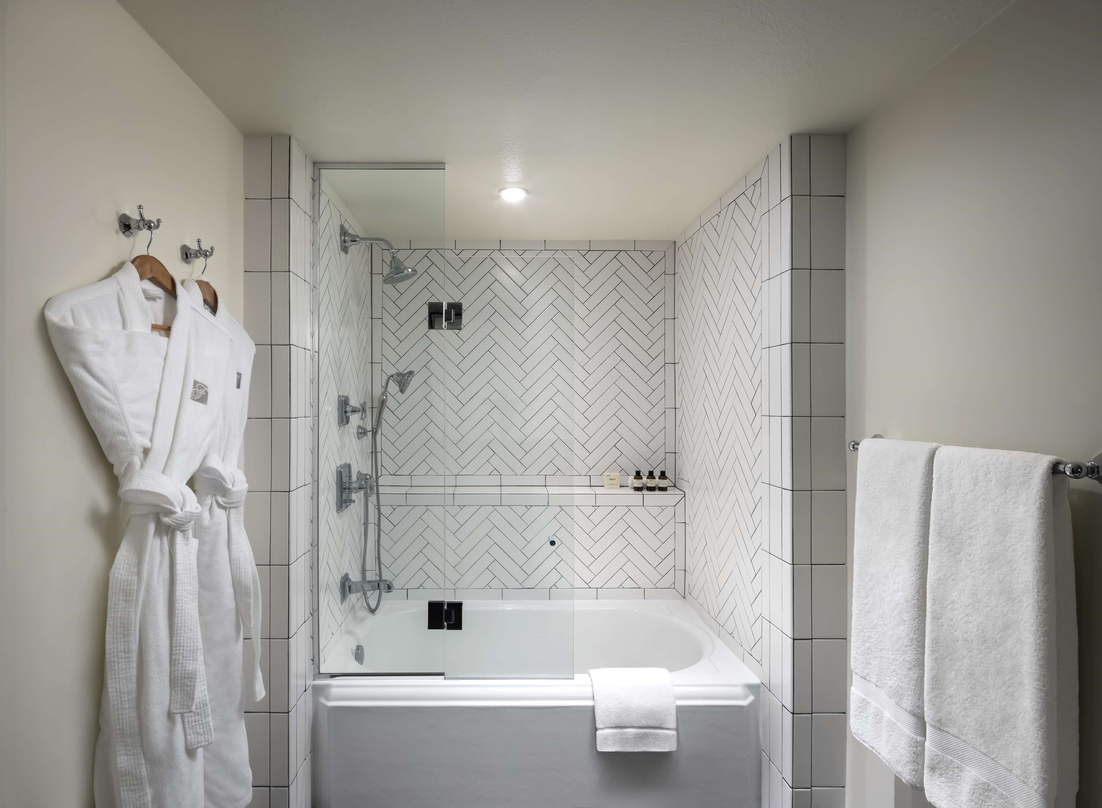 A modern bathroom with a glass-enclosed shower, a white bathtub, and a towel rack.