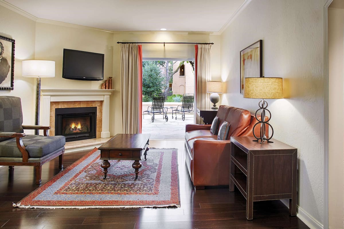 Una sala de estar con chimenea, televisión, sofá, mesa de centro y vistas al exterior.
