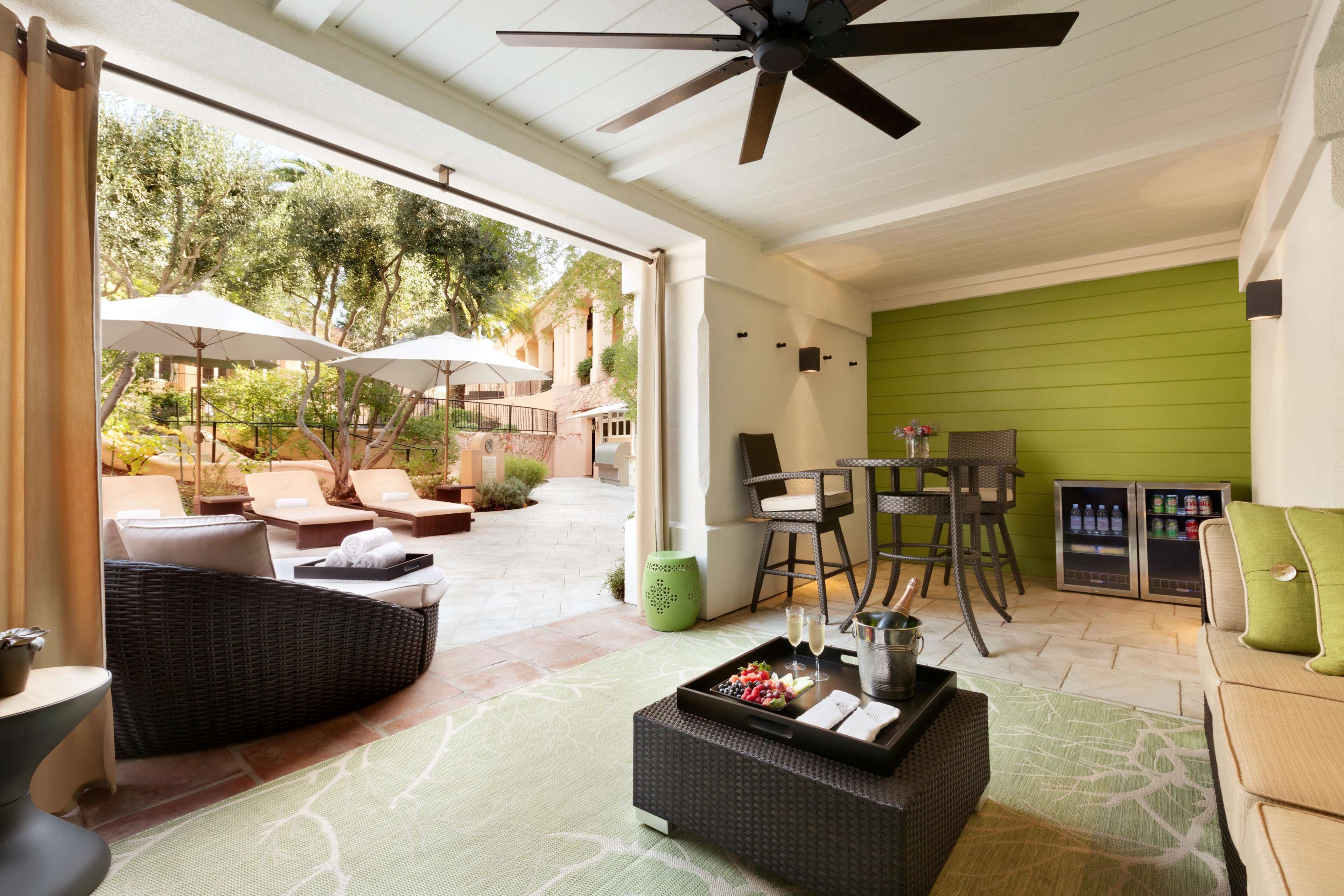 Un vaste patio doté d’un espace salon extérieur, d’un ventilateur de plafond et d’un mur d’accent de couleur verte.