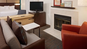 Une chambre d’hôtel avec un lit, une télévision, une cheminée et un canapé.