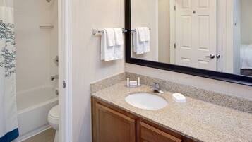 A bathroom with a sink, mirror, and towel rack.