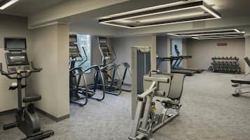Un gimnasio con cintas de correr, elípticas y equipo de pesas.
