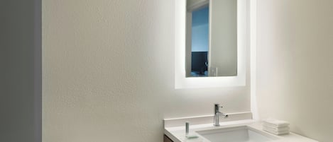 Un baño con lavamanos blanco, espejo y retrete.