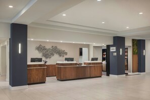 A modern reception desk with a digital screen, a wall art piece, and a sign that reads 'CRATE.'