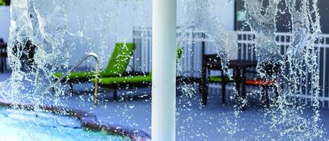 Una piscina al aire libre, sombrillas, sillones reclinables de piscina