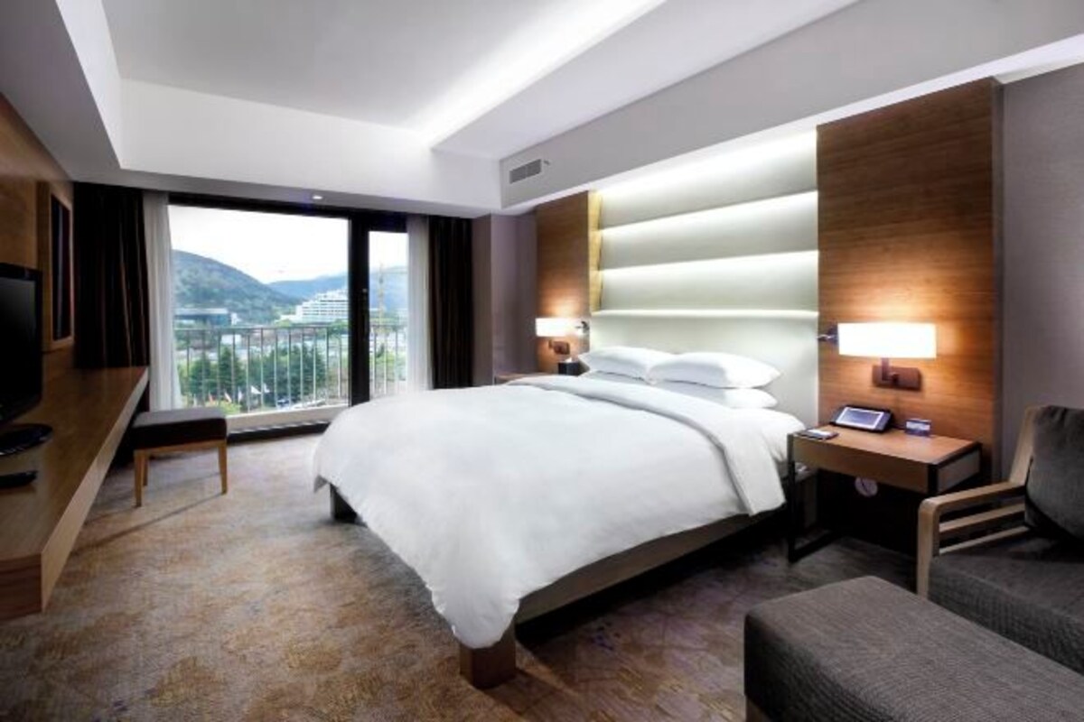 Une chambre d’hôtel moderne, dotée d’un grand lit, d’un bureau, d’une chaise et offrant une vue sur les montagnes.