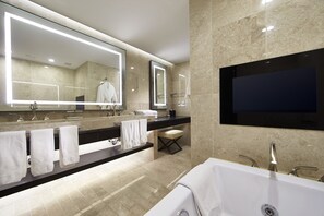 A modern bathroom with a large mirror, two sinks, a vanity, and a bathtub.