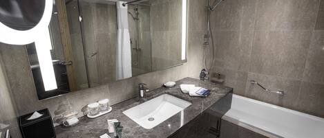 A modern bathroom with a large mirror, a white sink, a bathtub, and a shower area.