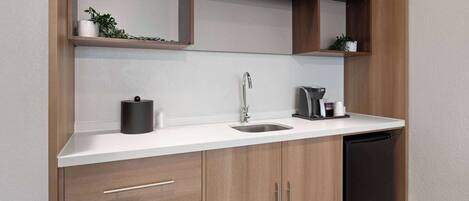 A modern kitchen with wooden cabinets, a white countertop, a sink, and a black dishwasher.