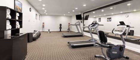 A modern gym with treadmills, an elliptical, and a weight bench.