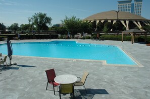 A swimming pool with a pavilion and lounge chairs in a landscaped area.