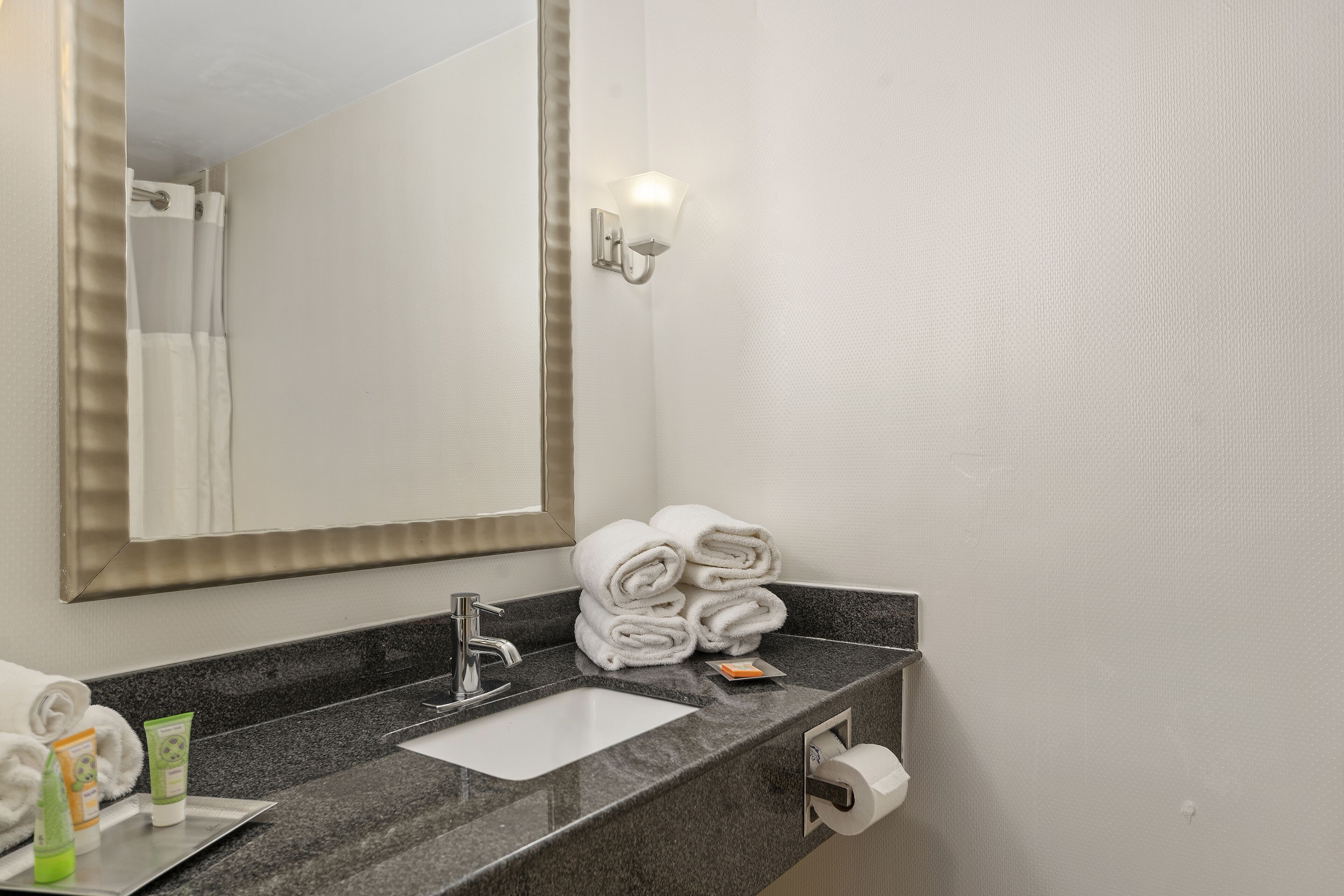 A bathroom with a sink, mirror, towel rack, and toiletries.