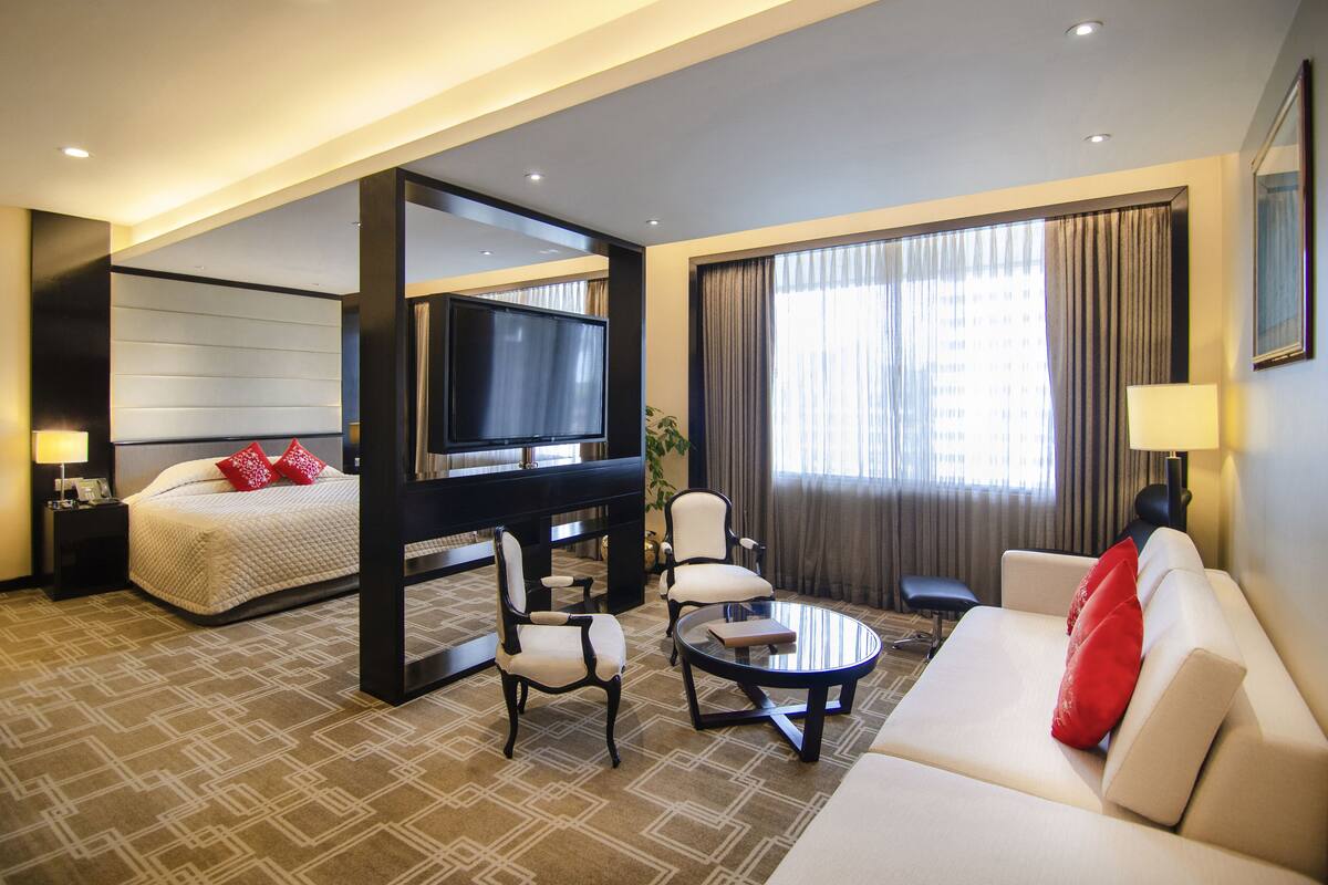 A hotel room with a bed, a TV, a sofa, and a coffee table.