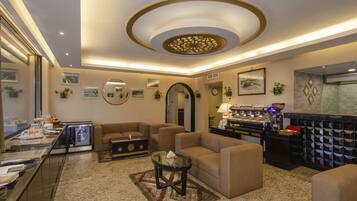 A modern hotel lobby with a seating area, a coffee station, and a buffet.