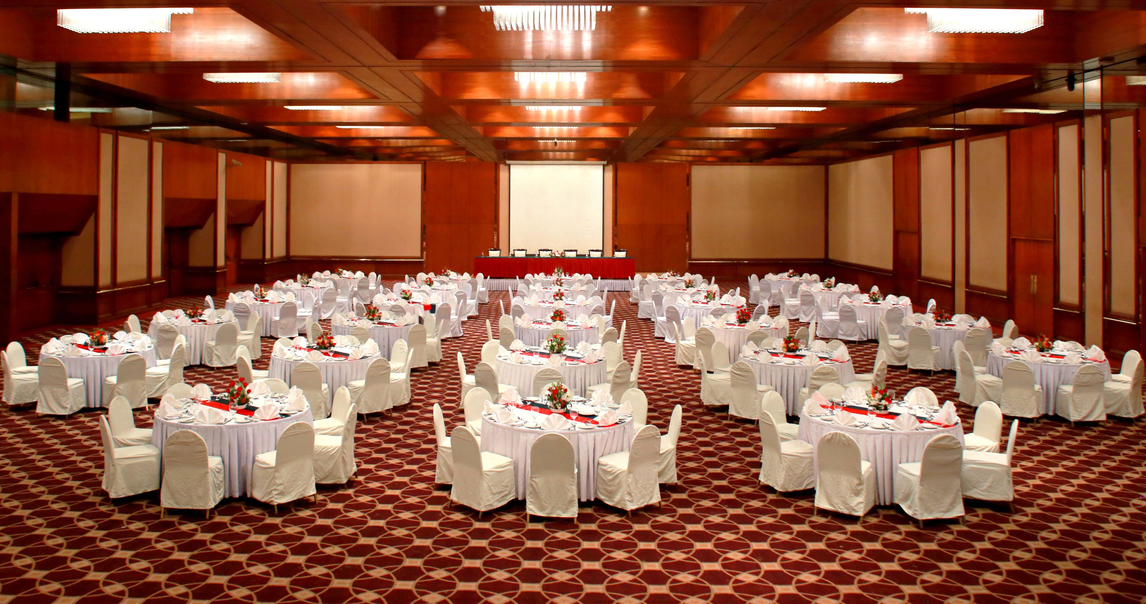 A large banquet hall with round tables and white chairs, arranged in rows.