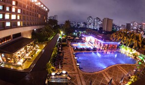 A nighttime view of a hotel with a pool area, outdoor seating, and a well-lit bar. - Pan Pacific Sonargaon Dhaka (Dhaka)