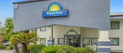 A Days Inn building with a sign, a covered entrance, and a landscaped area with plants.