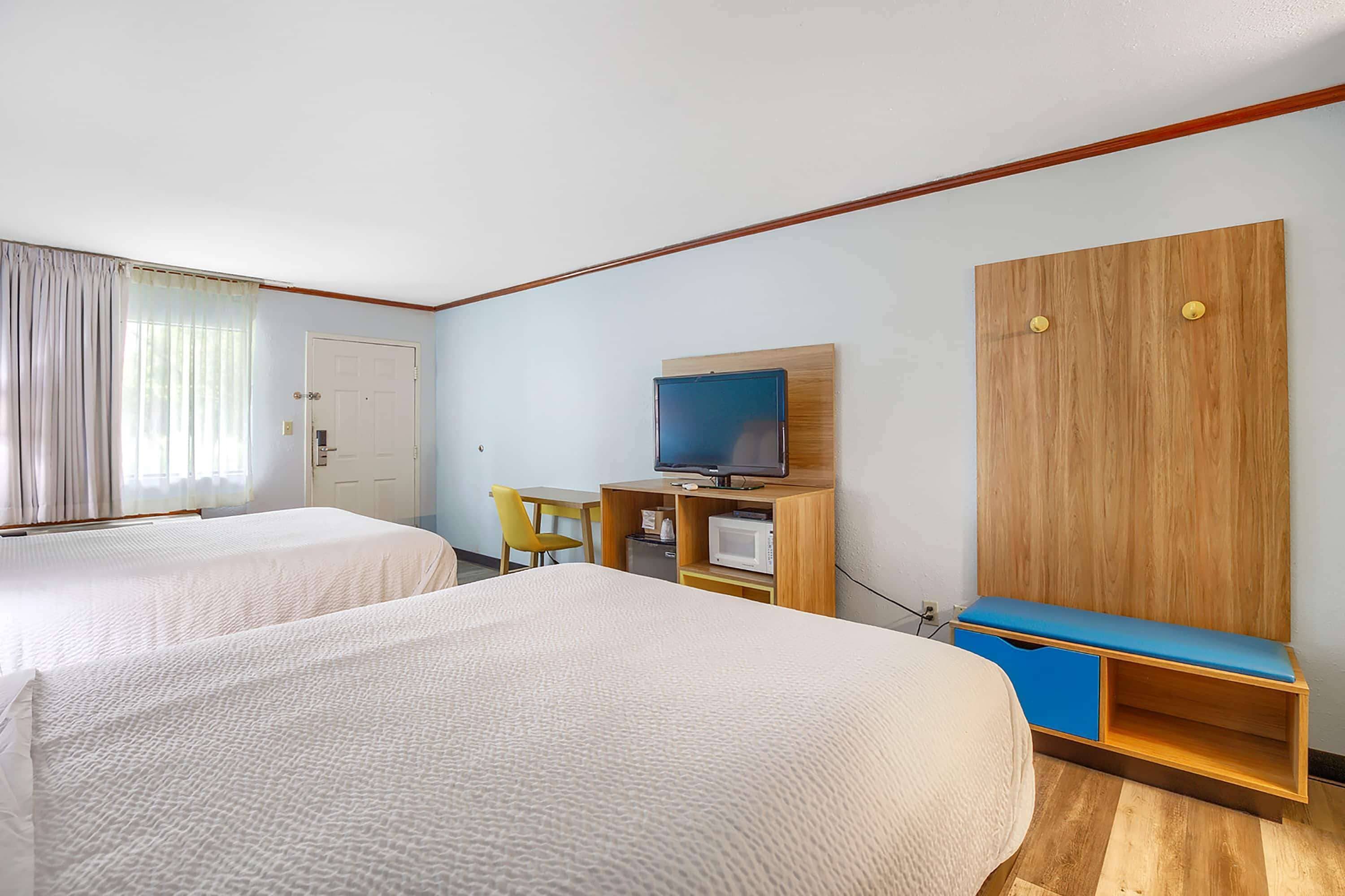Ett hotellrum med två sängar, en tv, ett skrivbord med en stol och en garderob.