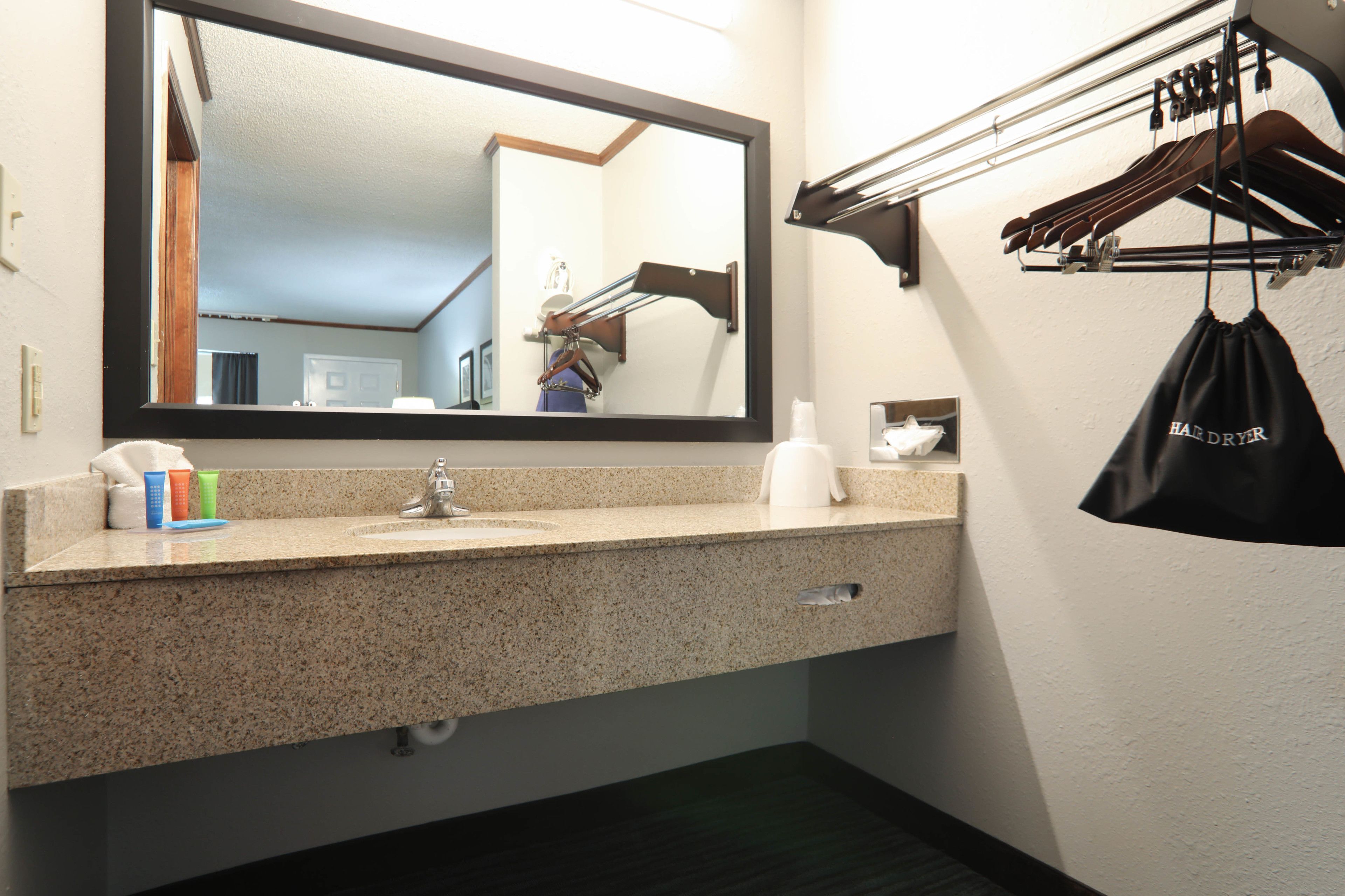 Un baño con encimera de granito, un lavabo, un espejo, un perchero con ganchos y un pequeño cajón para guardar objetos.