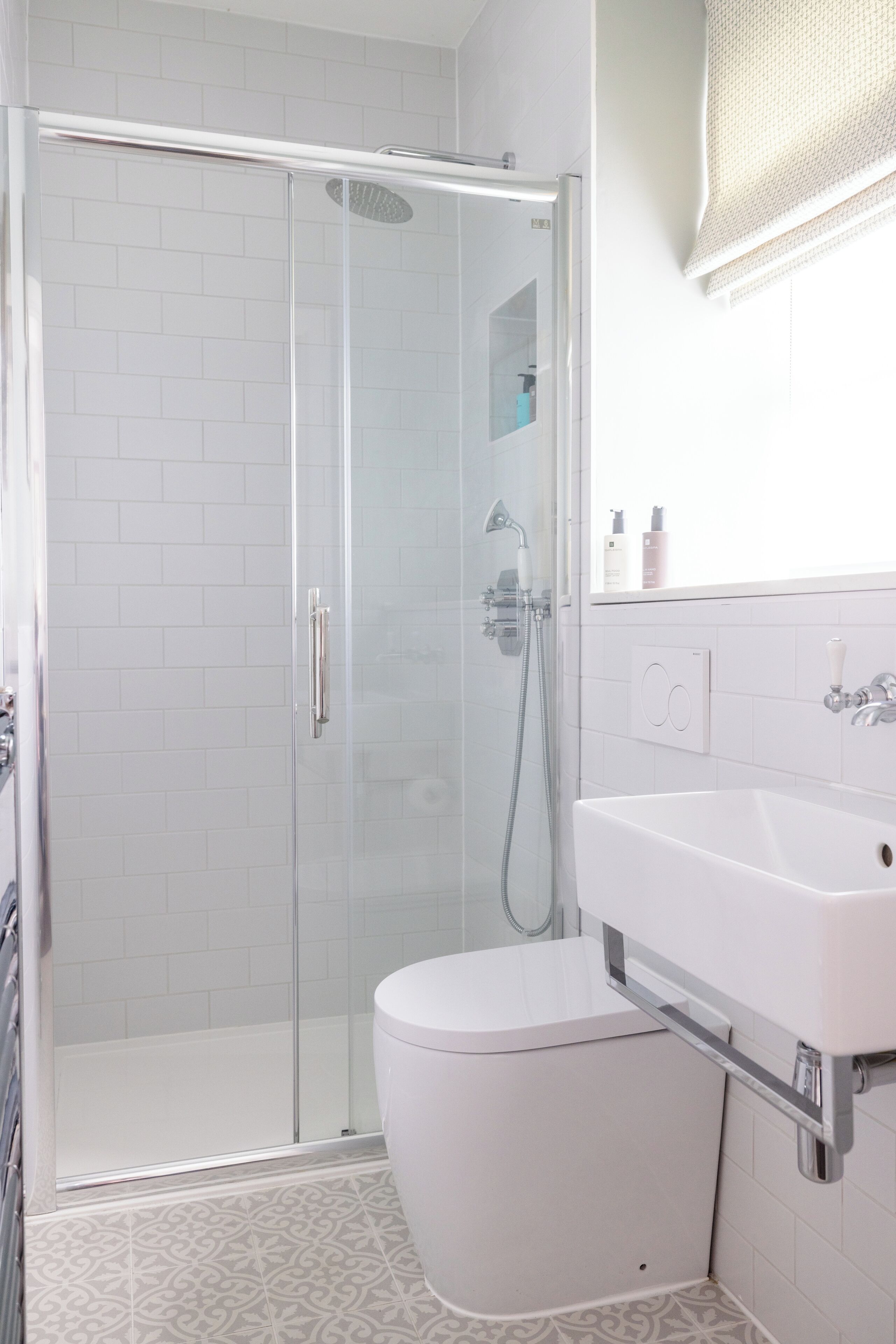 A modern bathroom with a glass shower enclosure, a white toilet, and a sink with a mirror above it.