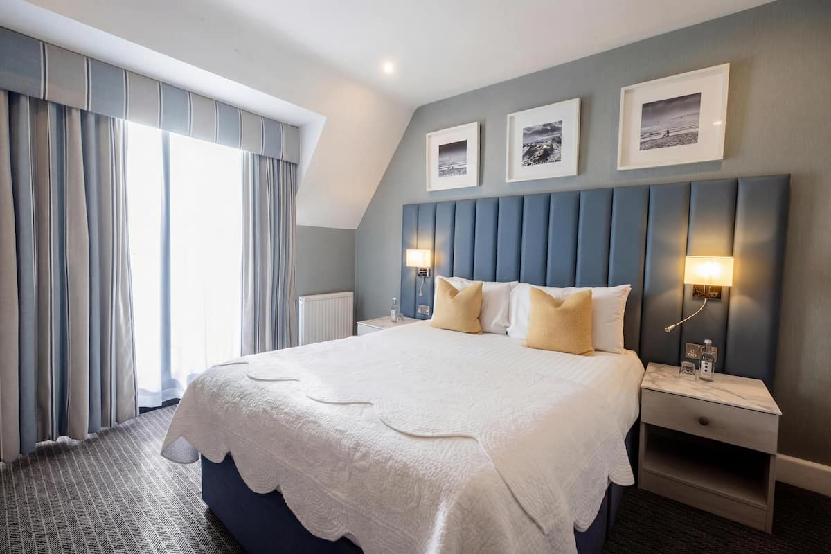Ein Hotelzimmer mit einem großen Bett, zwei Nachttischen, einer Kopfteil und drei gerahmten Bildern an der Wand.