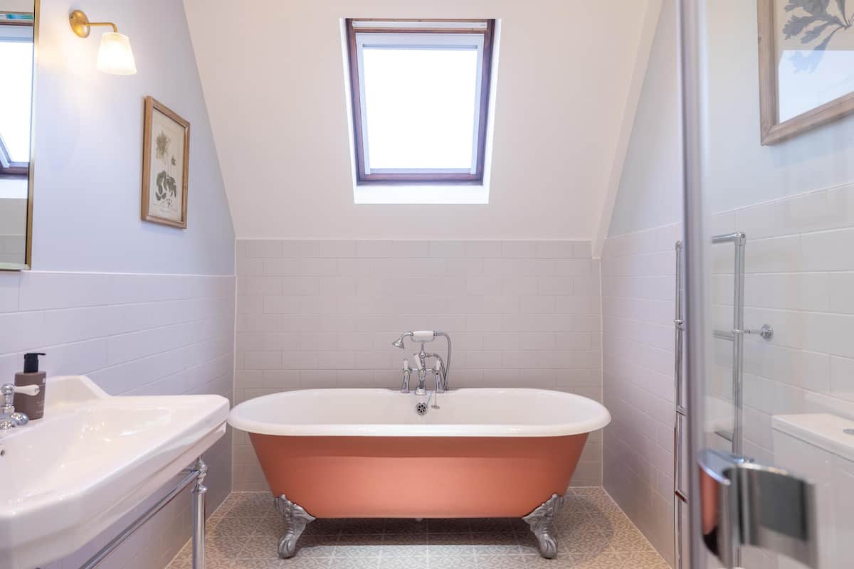 Ein Badezimmer mit einer freistehenden Badewanne, einem Waschbecken, einem Fenster und einer Duschkabine.