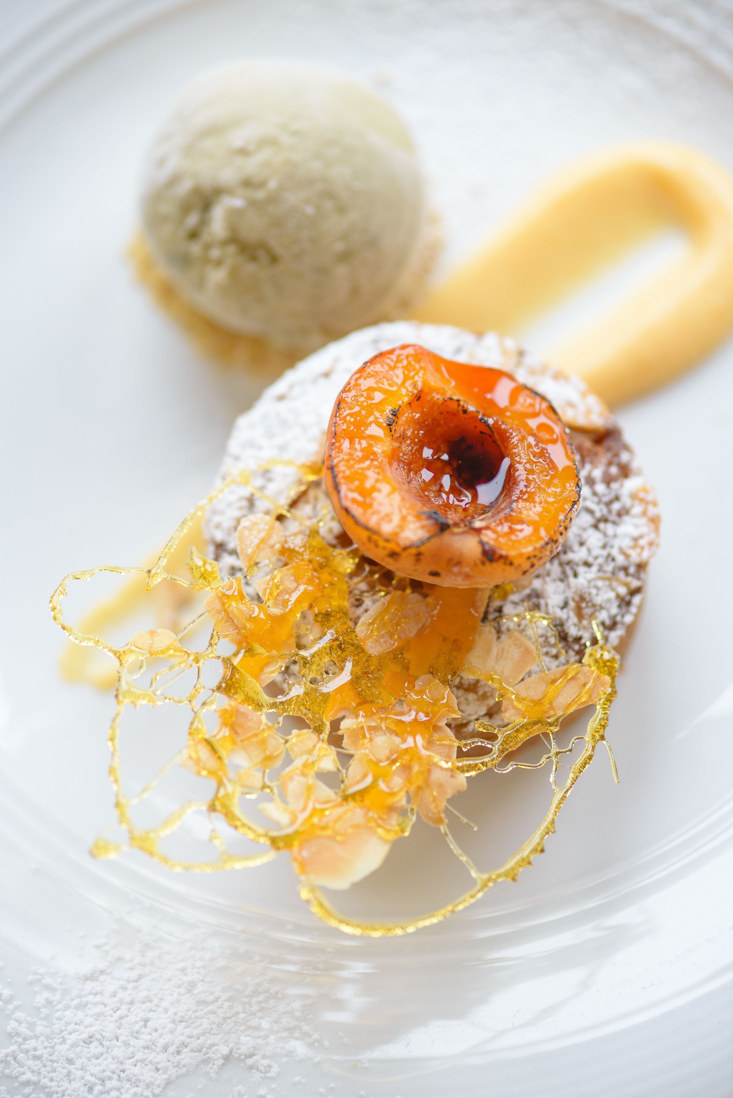 Een nagerechtopstelling met een bolvormig dessert en gekaramelliseerd fruit.