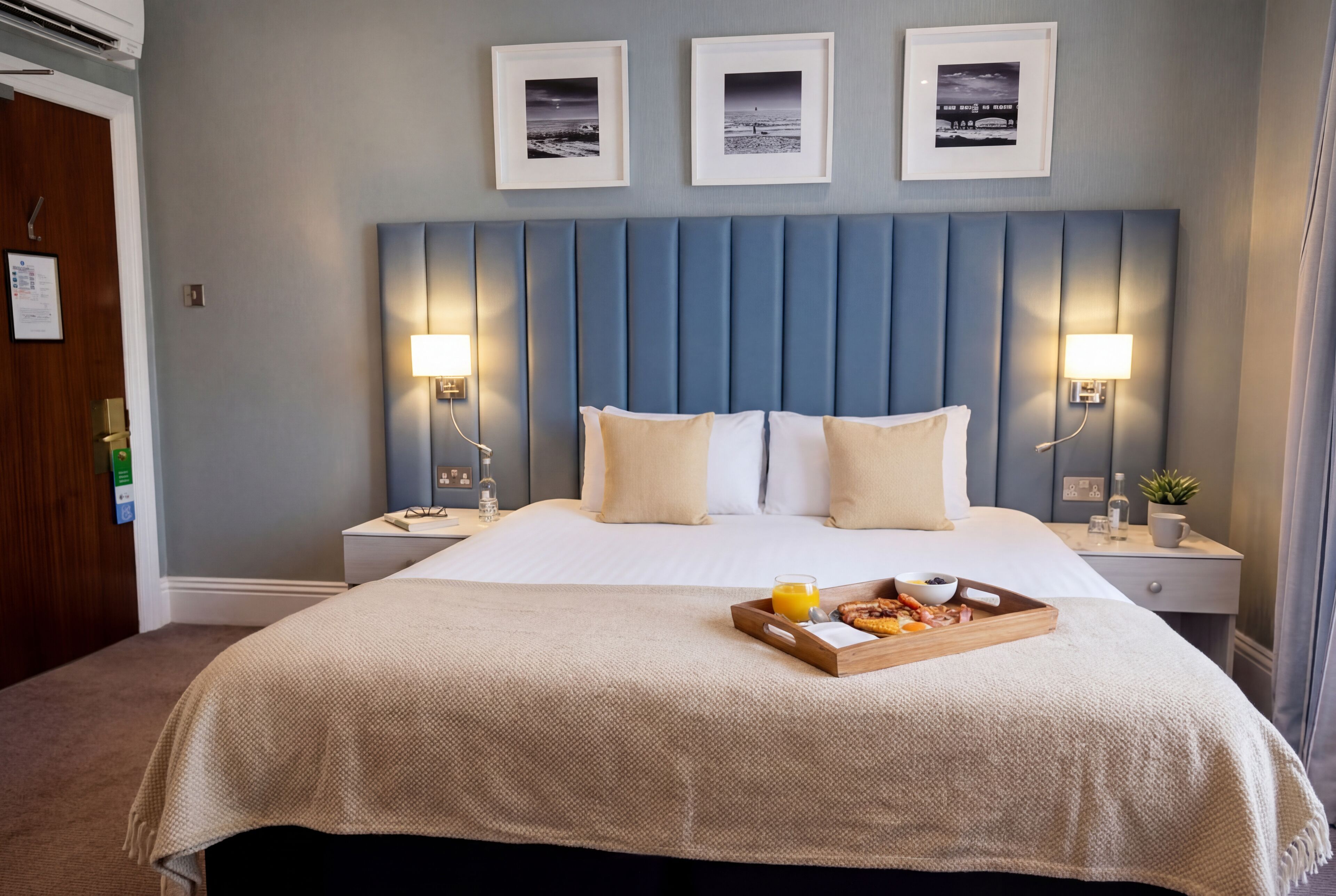 Quarto de hotel com uma cama grande, duas mesas de cabeceira, um painel de cabeceira e uma bandeja com itens de café da manhã.