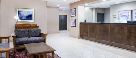 A lobby with a reception desk, a sofa, a coffee table, and framed artwork on the walls.
