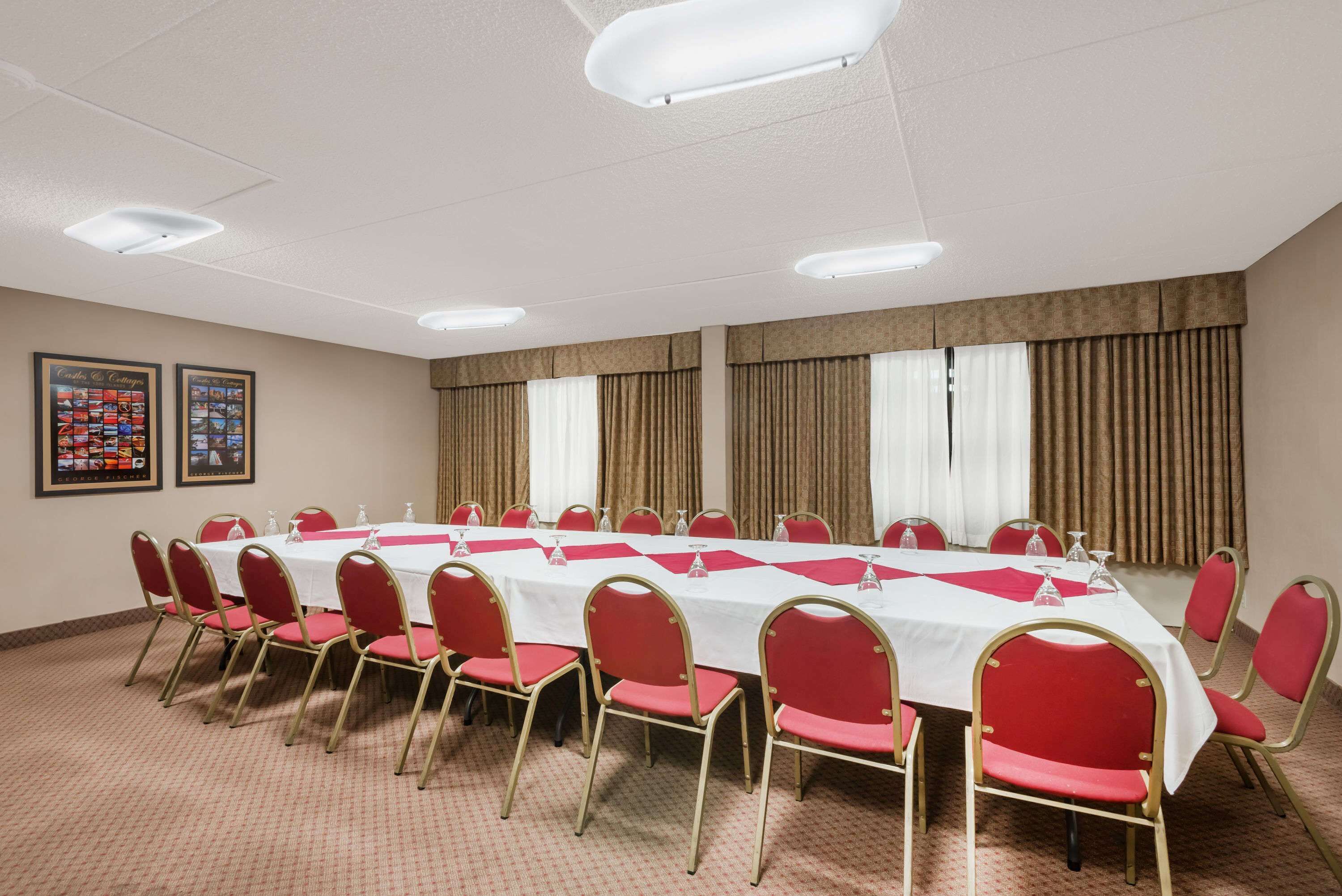 A conference room with a long table, red chairs, and white tablecloths.