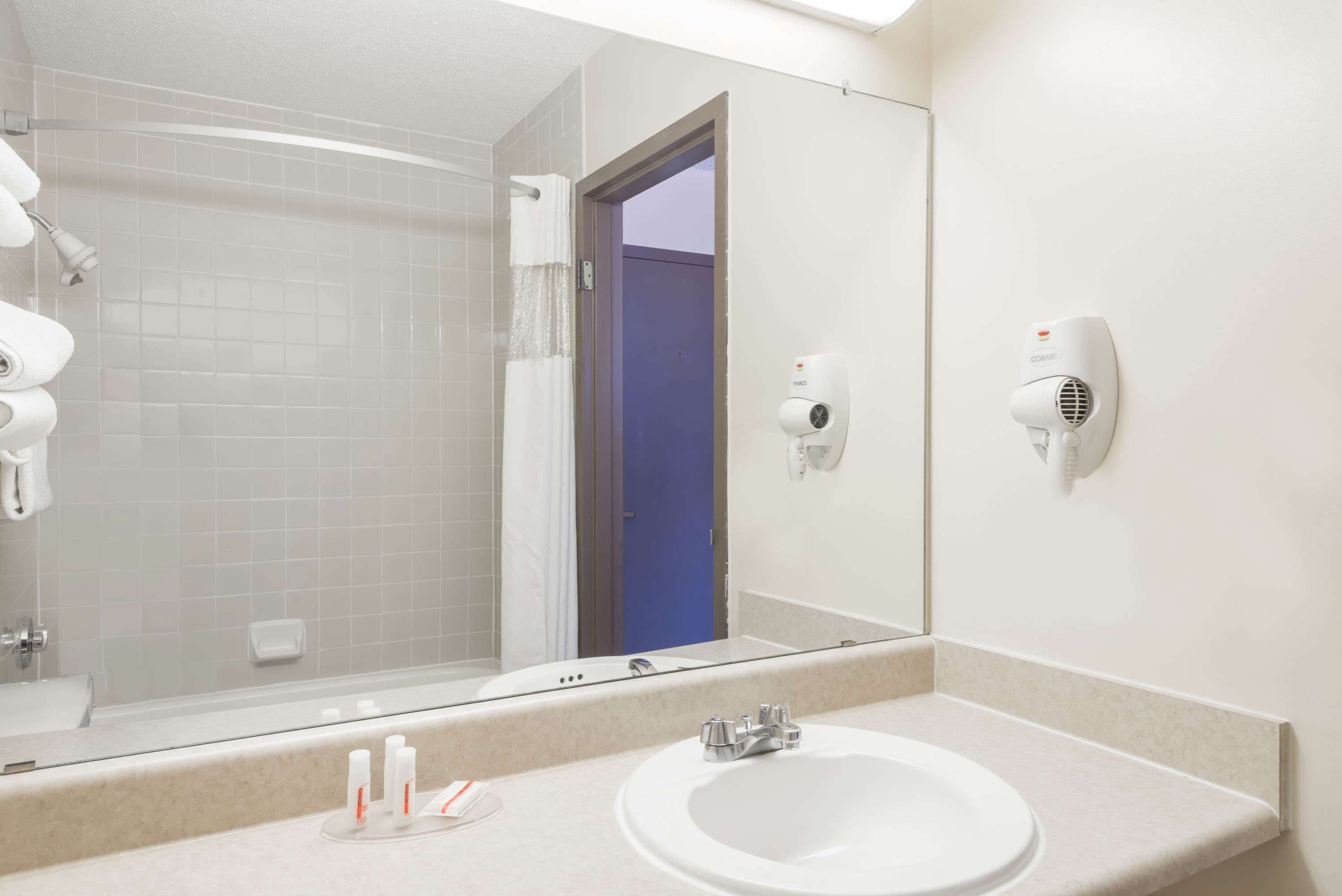 A bathroom with a sink, mirror, and towel rack.