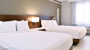 A hotel room with two beds, a nightstand, a lamp, and a large window with curtains.
