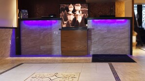 A reception area with a marble counter, a large screen displaying a fountain, and a patterned floor.