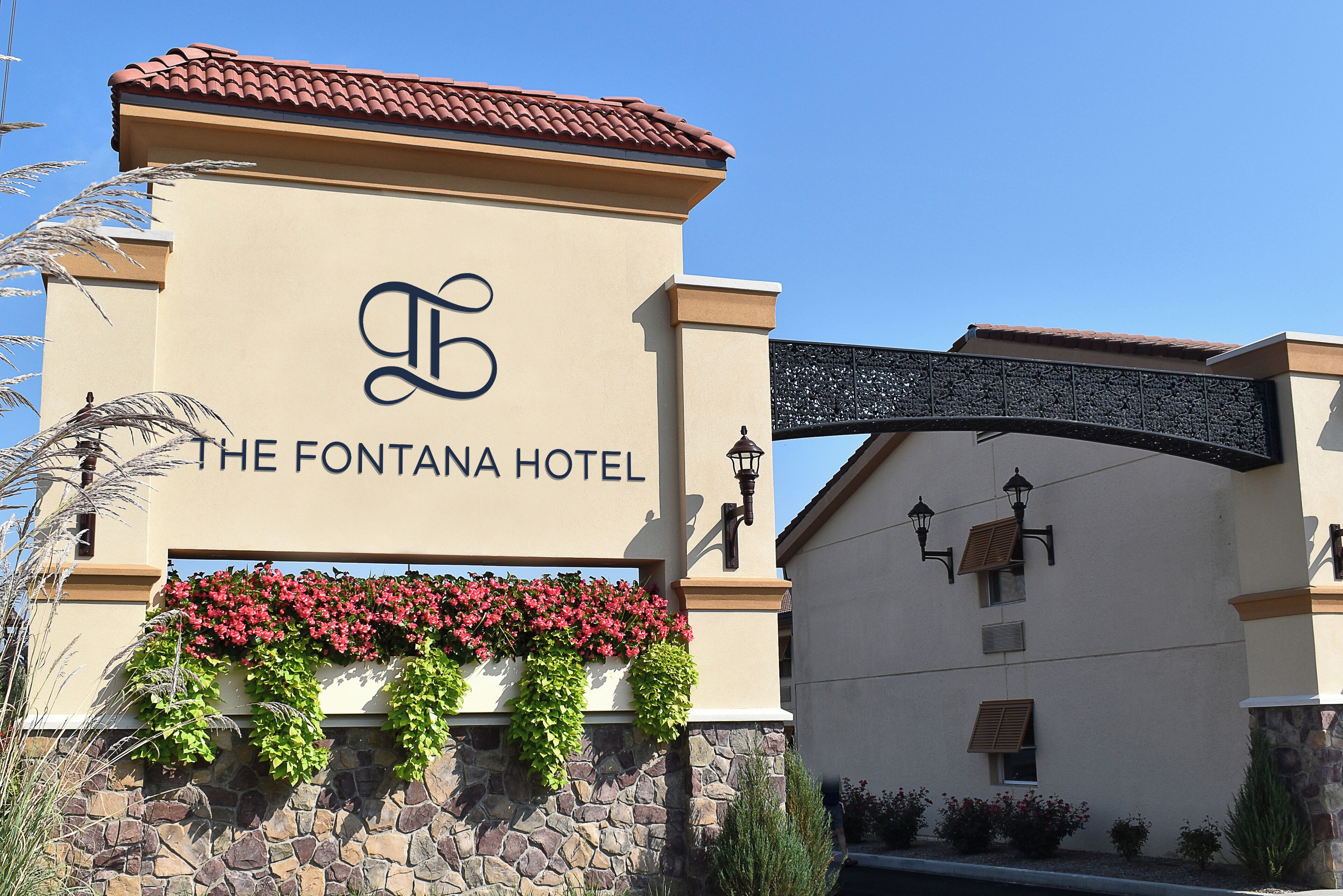 The exterior of The Fontana Hotel with a stone facade, a sign with the hotel's name, and a decorative archway.