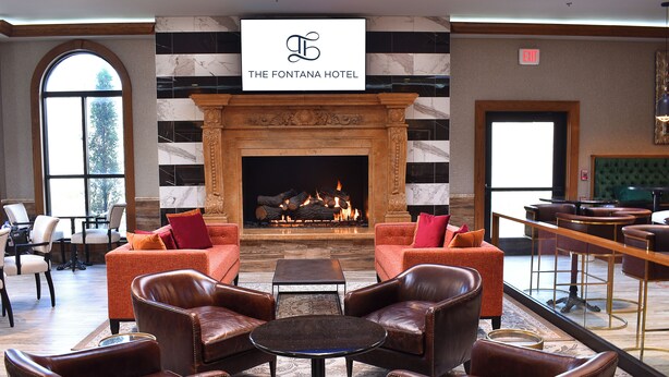 A lobby with leather sofas, a fireplace, and a sign for The Fontana Hotel.