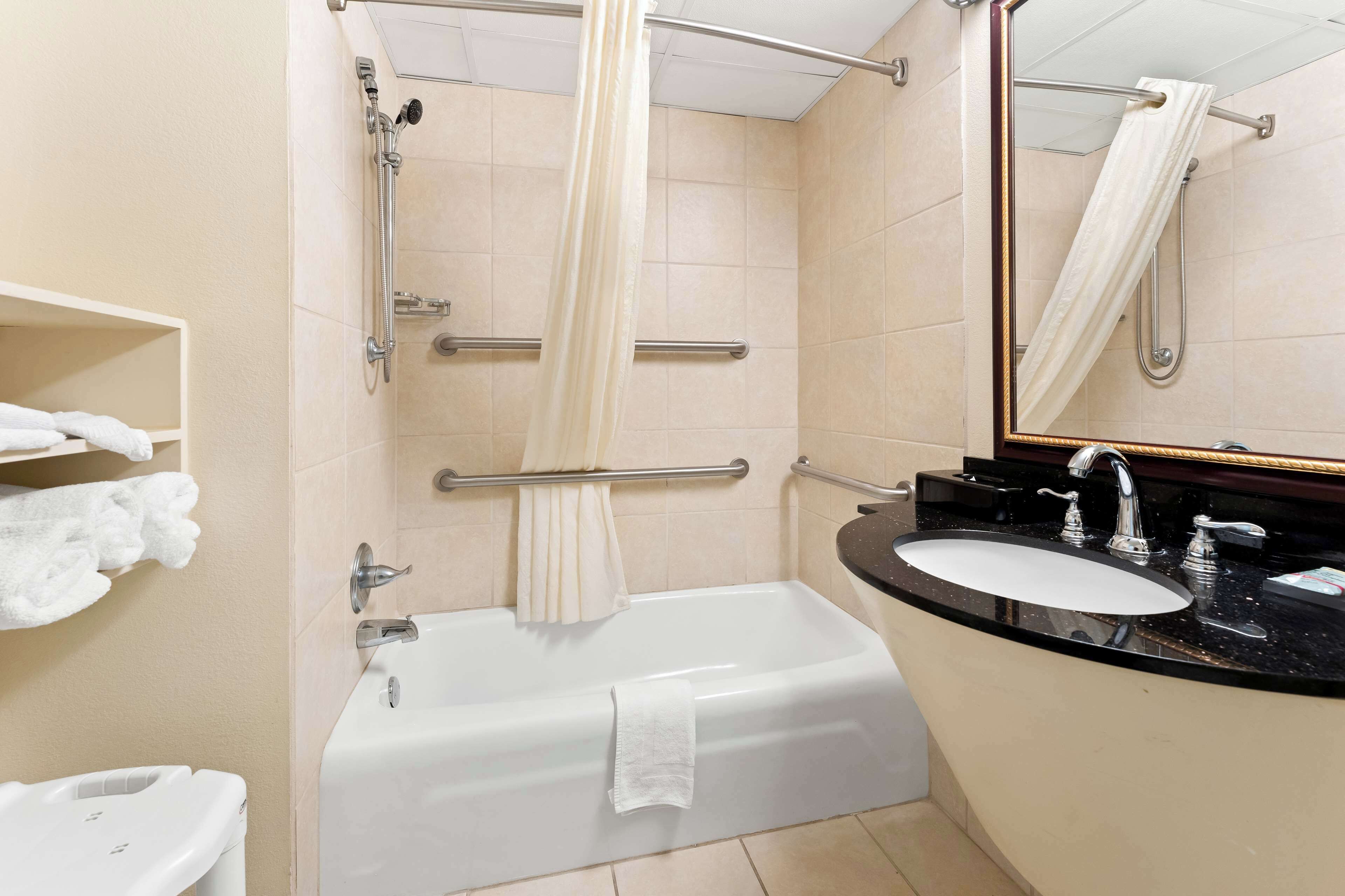 Une salle de bain avec une baignoire, un lavabo, un miroir et un porte-serviettes.