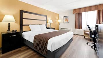 Habitación de hotel con una cama grande, dos mesitas de noche con lámparas, un escritorio con silla y una ventana con cortinas.