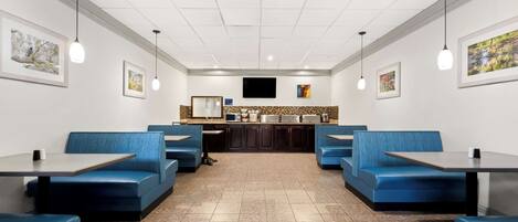A restaurant with blue booths, a counter, and a flat-screen TV.