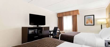 A hotel room with two beds, a desk with a television, a chair, and a window with curtains.