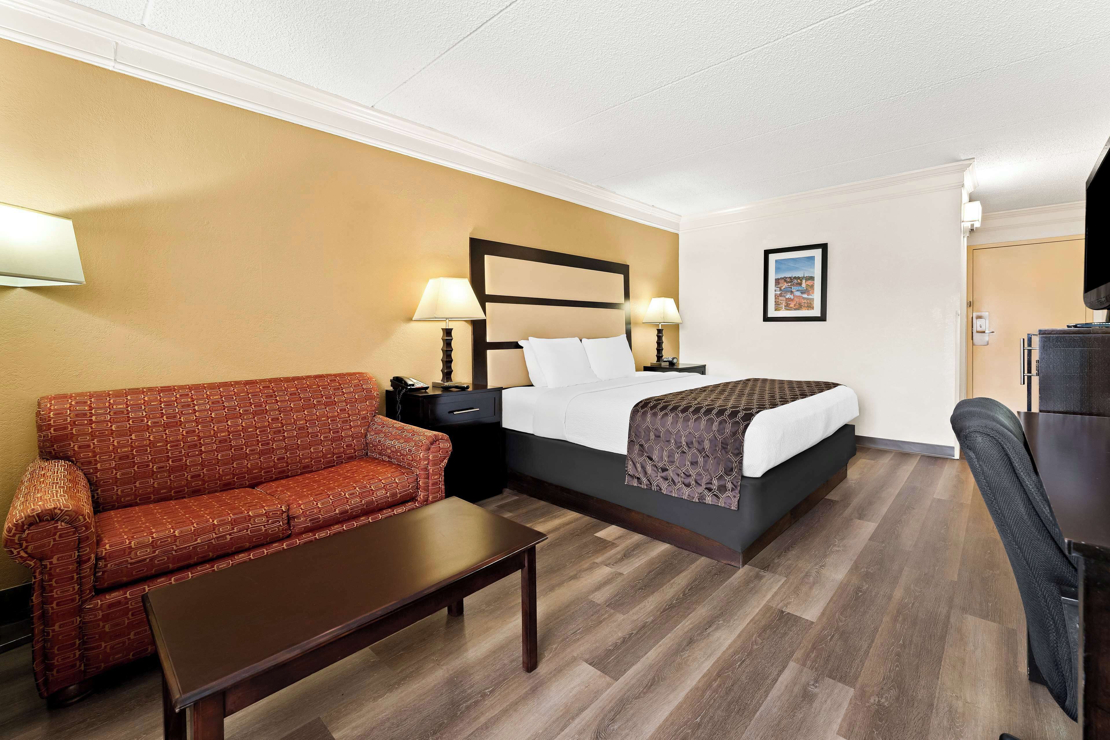 A hotel room with a bed, a sofa, a table, and a TV.