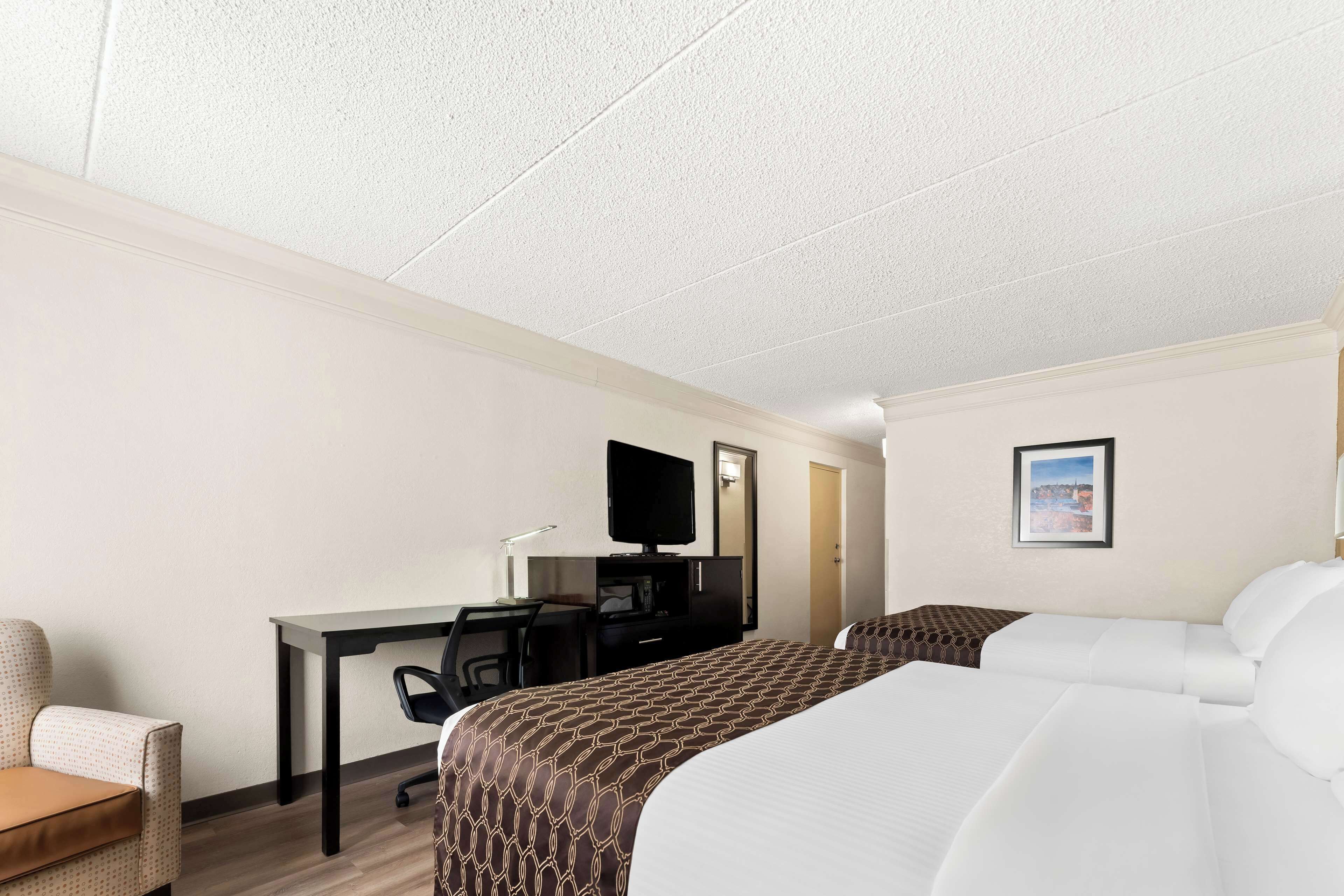 A hotel room with a bed, a desk, a chair, a television, and a framed picture on the wall.