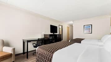 Une chambre d’hôtel avec un lit, un bureau, une chaise, une télévision et un tableau encadré au mur.