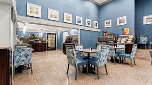 A restaurant with blue walls, framed pictures, and blue chairs with leaf patterns. - Best Western Riverside Inn (Macon)