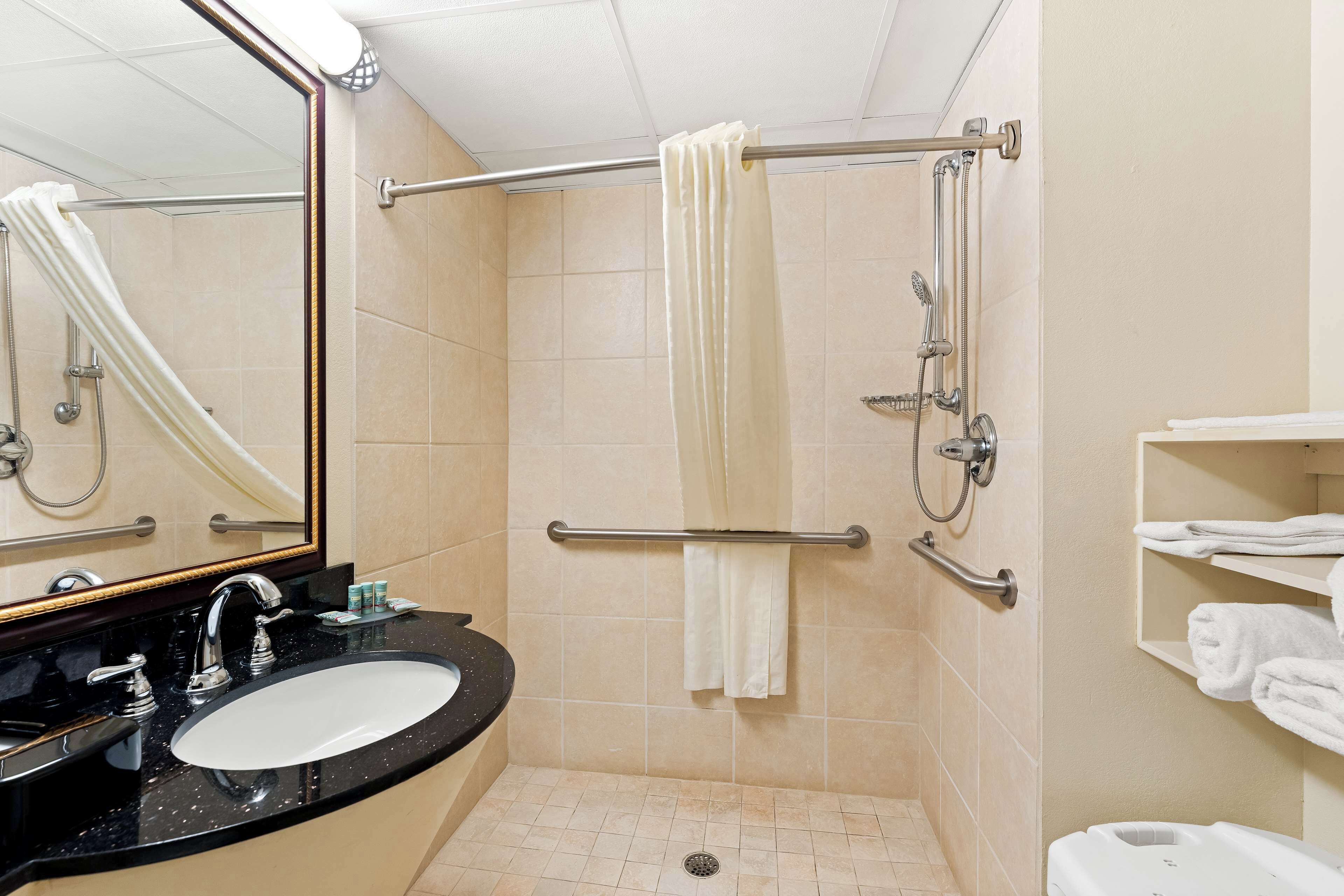A bathroom with a sink, mirror, shower, and towel rack.
